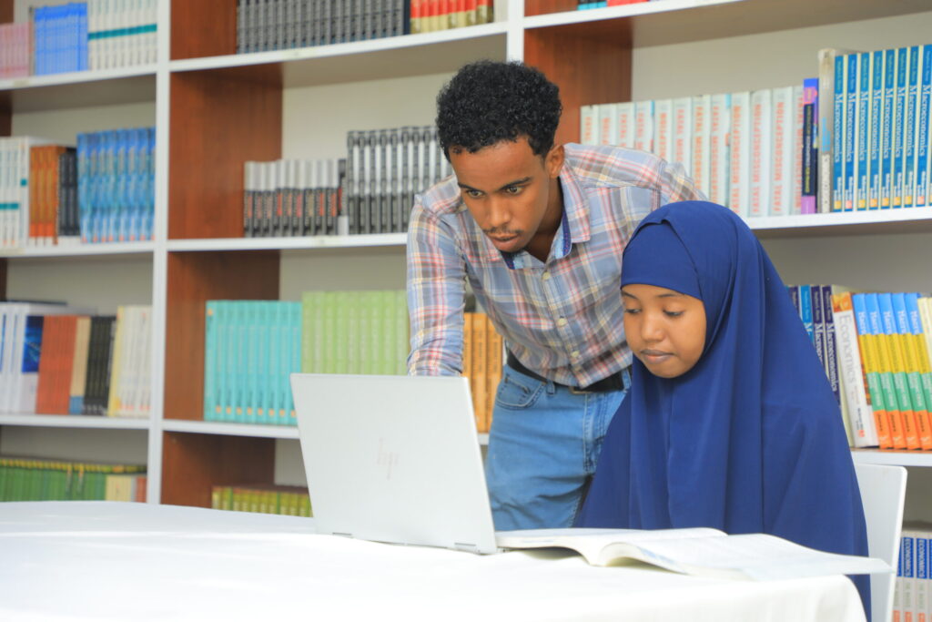 A researcher helping a student with her laptop in the library